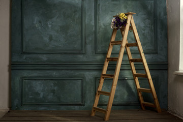 Decorated wedding interior with bouquet on wooden step ladder