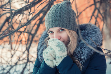 girl warms her hands in mittens