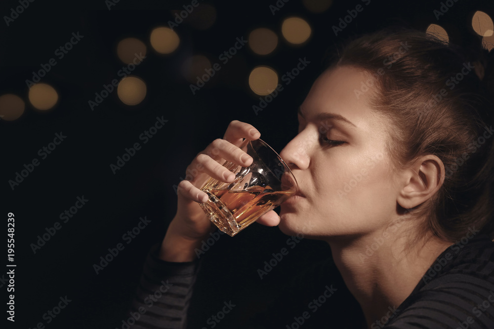 Young woman drinking alcohol in bar