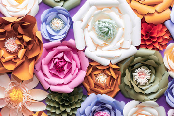 Colorful paper flowers on wall. Handmade artificial floral decoration.  Spring abstract beautiful background and texture