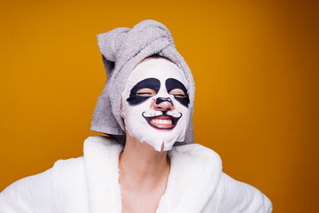 Wall Mural - happy woman with a towel on her head apply moisturizing mask on face