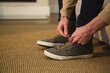 © Wavebreak Media - Man tying shoelaces in living room at home