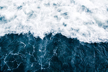 the blue surf of the sea with white waves, splash, foam and bubbles, aqua abstract background