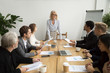 © fizkes - Serious aged businesswoman leading corporate team meeting talking to multiracial employees, senior female boss ceo leader discussing work with diverse subordinates at company group briefing