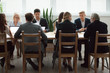 © fizkes - Serious multi-ethnic business people team sitting at conference table, senior executives working together with young managers at office staff meeting, focused group negotiations or teamwork concept