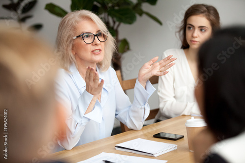Fotografía Attractive aged businesswoman, teacher or mentor coach speaking to young people,