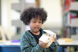 © Nattanon - Very happy African ethnicity boy with White House Wooden in hands laughing happily. Children Learning Class in Library. Setup studio shooting.