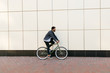 Side view of a stylish bearded man riding a bicycle on the city street.