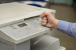 angry young business man beats his fist on a multifunction printer or copier
