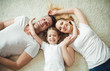 © My Ocean studio - Top view of Young happy family. Beautiful and smiling father and mother with daughter lying on the floor at home and hugging looking at the camera.