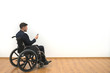 © realstock1 - The man in a wheelchair phones on the white wall background