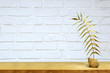 Złoty liść na półce na tle białej ścianie z cegły.
