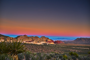 sun setting over redrock canyon rocks with las vegas in background