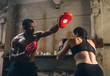 © BONNINSTUDIO/Stocksy - Strong brunette woman boxing indoors with his coach.