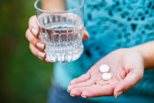 Girl Holds A Glass Of Clean Water And Two White Pills
