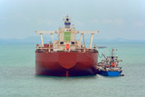 Fototapeta Desenie - Loading anchored oil supertanker via a ship-to-ship oil transfer (STS) from raid tanker