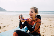 Woman In Wetsuit Taking A Photo With Action Camera