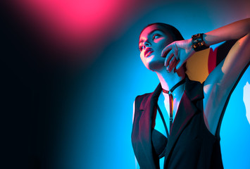 Sexy young brunette girl in black clothes, fashion accessories posing in studio over colorful background