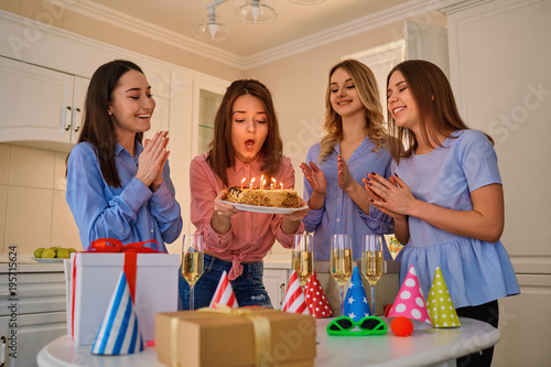 Zdjęcie XXL Grupa dziewczyn z ciastem ze świeczkami obchodzi urodziny w pokoju.