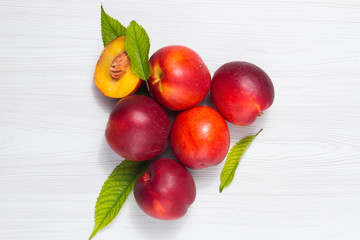 Wall Mural - Peaches with leaves on a white wooden table Top view