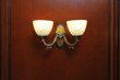 Beautiful double lamp-sconces on a wooden brown wall