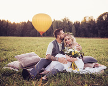 Lovely Young Couple In Wedding Dresses In Bohho Style, On A Field With A Balloon