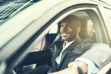 Canvas Print - African businessman smiling while driving his car in the city