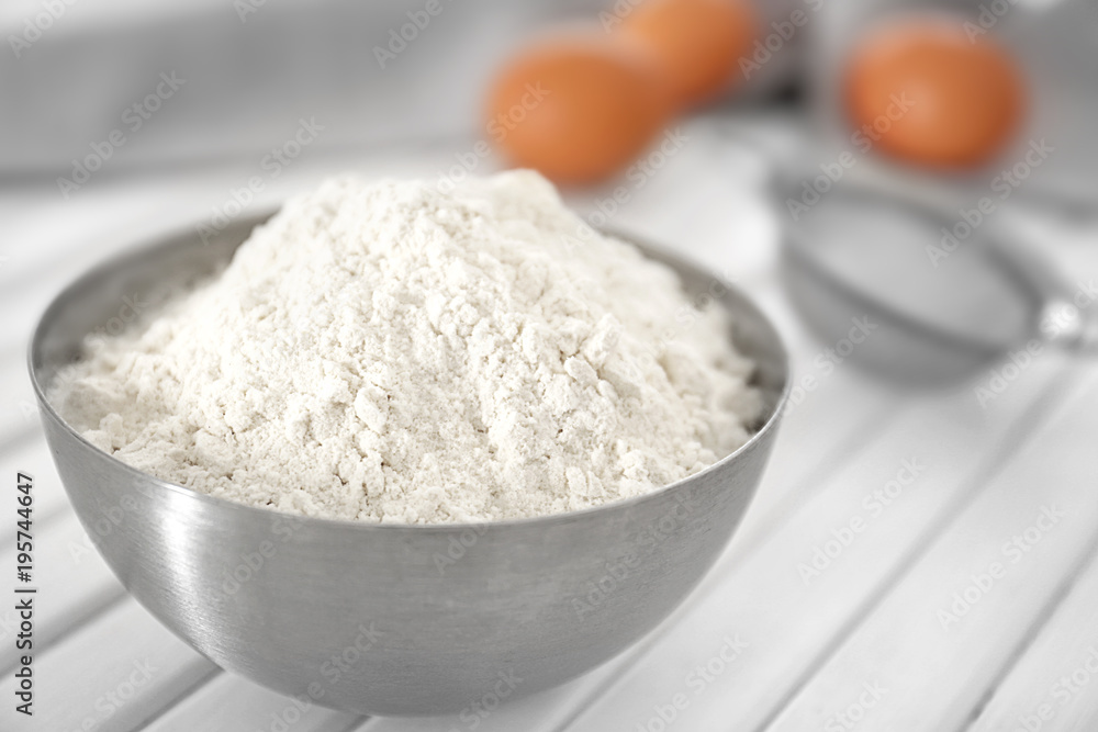 Bowl with wheat flour on white table, closeup