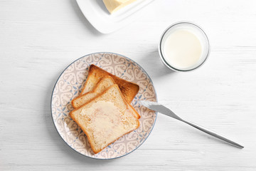 Canvas Print - Plate with tasty toasted bread and glass of milk on wooden table