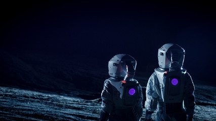 Wall Mural - two astronauts in space suits standing on the alien planet look at dark sky. space travel, habitable