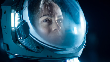 Wall Mural - portrait shot of the courageous female astronaut wearing helmet in space, looking around in wonder. 