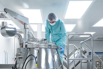 Wall Mural - Pharmaceutical factory man worker in protective clothing operate production line in sterile working conditions