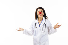 Portrait Of A Smiling Female Doctor With A Red Clown Nose And Both Hands Out, Palms Up, Isolated On White Background