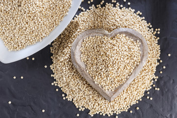 Wall Mural - Quinoa grains with spoon and bowl on black background