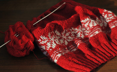 Wall Mural - Needlework. Homemade knitting from red and white wool with knitting needles. Close-up.