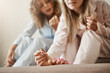 © Cookie Studio - She can make nails better than in salon. Cropped shot of young blonde girl in nightwear sitting with friend at home, painting fingernails and discussing latest news and gossips, having girly talk