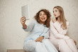 © Cookie Studio - Daughter and mother making family photo while relaxing at home. Emotive beautiful mom taking selfie with cute bestie while both in nightwear, making faces and shh gesture as if having secret