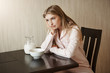© Cookie Studio - Daughter is fed up of same breakfast every day. bothered and annoyed young woman in nightwear leaning on hand while sitting near bowl of cereals and milk, being angry or sulking