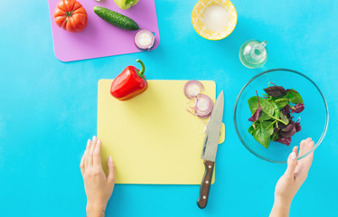 Canvas Print - Healthy food concept. Diet food. Woman hands cooking summer vegetarian salad on blue background