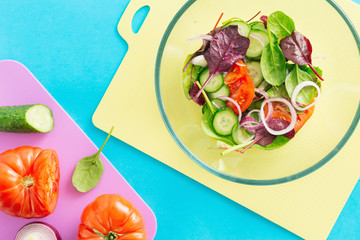 Close up bowl fresh summer salad on blue background, top view. Healthy food concept. Diet food