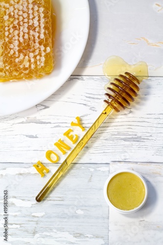 Fotografie, Obraz tasty organic honey in a honeycomb and honey lip balm on a wooden, vintage backg