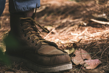 Closeup image of a man wearing boots while trekking in a tropical forest