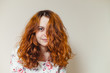 © Daniil - Portrait of beautiful cheerful redhead girl with curly hair over beige background. Hair dyed with henna. Professional hair care.