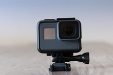 Black 4K action camera on top of a wooden table against a light background