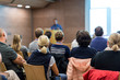 © kasto - Business and entrepreneurship symposium. Speaker giving a talk at health care workshop meeting. Audience in conference hall. Rear view of unrecognized participant in audience.