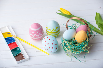 Wall Mural - Colorful Easter eggs with paints hand painted on a white wooden background. Festive spring card