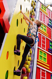 Fototapeta Londyn - Little girl on climbing wall in entertainment center.
