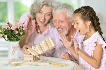 Poster - grandparents and granddaughter playing with wooden blocks