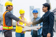 © smilepoker - Handshake between engineer and manager, team meeting outdoor using blueprint