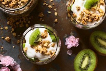 Wall Mural - Yogurt parfait with fresh kiwi and crunchy almond and oatmeal granola in glasses, photographed overhead on slate with natural light (Selective Focus, Focus on the top of the parfait)